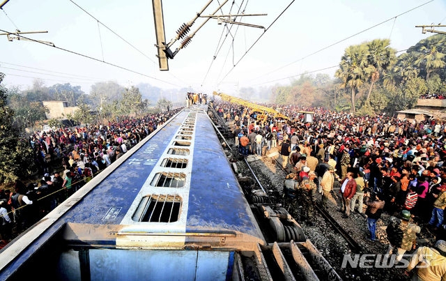 【파트나=AP/뉴시스】인도 비하르주 파트나 북쪽 약 30㎞ 지점에서 3일 발생한 열차 탈선 사고 현장에서 많은 구경꾼들이 몰린 가운데 구조대원들이 전복된 차량 안에 갇힌 생존자들을 구출하고 있다. 이 사고로 최소 7명이 사망하고 10명이 부상했다.