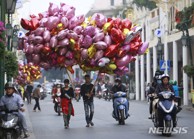 3일(현지시간) 베트남 북부 도시 하노이에서 풍선 판매원들이 커다란 풍선 꾸러미를 들고 거리를 걷고 있다. (출처: 뉴시스)