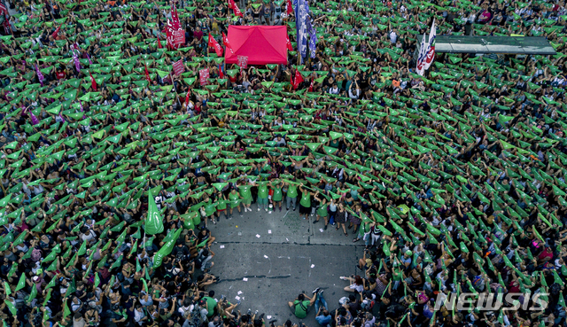 【부에노스아이레스=AP/뉴시스】19일(현지시간) 아르헨티나 수도 부에노스아이레스 국회의사당 앞에서 자발적 임신중지(낙태) 합법화를 촉구하는 시위대가 녹색 스카프를 들고 시위하고 있다. 앞서 아르헨티나 하원은 임신 14주까지는 임신중지(낙태)가 가능하도록 하는 법안을 통과시켰는데 이는 낙태가 불법인 상황에서 안전하지 않은 낙태 시술을 받다가 숨지는 여성들이 끊이지 않아 10년 전부터 여성들이 거리로 나와 법 개정을 촉구하면서 가능해진 일이다. 시위대가 착용한 녹색 스카프는 임신중지 합법화 운동의 상징이 됐다.