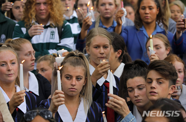 18일(현지시간) 뉴질랜드 크라이스트처치의 알 누르 모스크 외곽에 학생들이 모여 지난 금요일 총기 난사 희생자들을 추모하기 위해 촛불을 들고 애도하고 있다. (출처: 뉴시스)