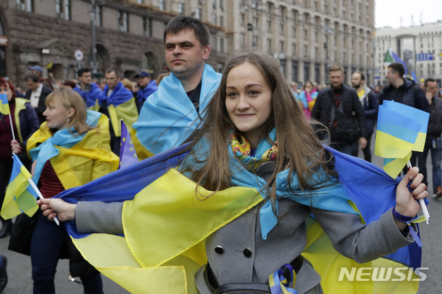 【키예프(우크라이나)=AP/뉴시스】 우크라이나 국기를 몸에 두른 페트로 포로셴코 현 우크라이나 대통령 지지자들이 19일(이하 현지시간) 수도 키예프에서 열리는 대통령 후보 간 토론회 참석을 위해 올림픽 경기장으로 행진하고 있다. 오는 21일 우크라이나의 대선 결선투표를 앞둔 19일은 선거 유세 마지막 날이며 20일에는 모든 후보의 선거운동이 금지된다. 2019.04.19.