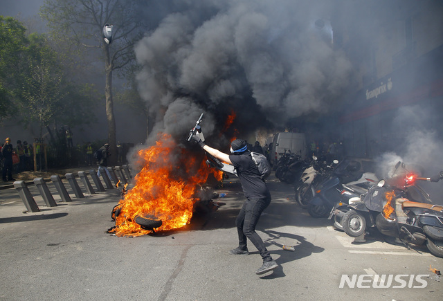프랑스 파리에서 노란 조끼 시위대가 시위하는 가운데, 한 남성이 스쿠터를 불타는 오토바이에 던지고 있다(출처: 뉴시스)