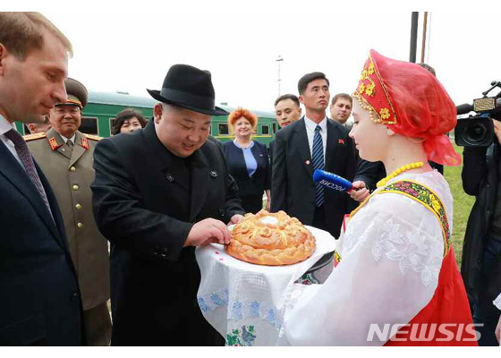 김정은 북한 국무위원장이 25일 북한-러시아 접경 하산역에 도착해 전통의상을 입은 러시아 여인으로부터 환영의 뜻을 가진 빵과 소금을 받고 있다. (출처:뉴시스)
