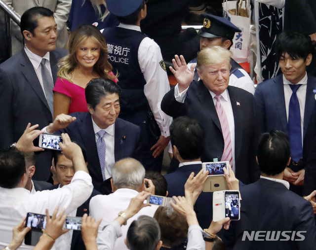 트럼프 미국 대통령이 아베 신조 일본 총리와 함께 26일 오후 도쿄에서 스모 경기장에 입장하면서 환호하는 관람객들을 향해 손을 흔들고 있다. 그 뒤를 멜라니아 여사가 따르고 있다(출처: 뉴시스)