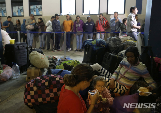 베네수엘라 이주민들이 최근 페루 툼베스의 국경검문소 이민담당 사무실 앞에 줄서 차례를 기다리는 가운데 또다른 이주자 가족이 바닥에 앉아 휴식을 취하고 있다(출처: 뉴시스)