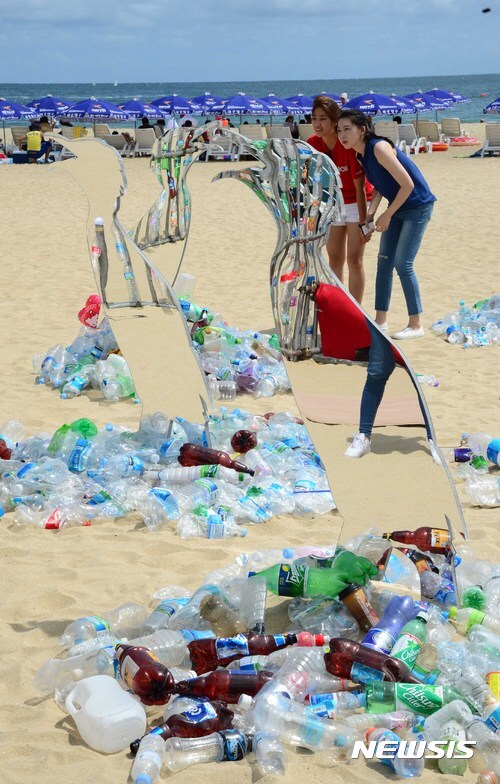 13일 부산 해운대해수욕장에서 국제환경단체 '그린피스' 활동가들이 일회용 플라스틱으로 뒤덮인 해변을 표현한 미술작품을 설치하고 있다. (출처: 뉴시스)