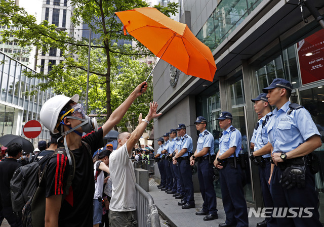 21일(현지시간) 홍콩 경찰본부 앞에서 범죄인 인도법안반대 시위를 벌이던 한 남성이 경찰을 향해 우산을 들어 보이고 있다(출처: 뉴시스)