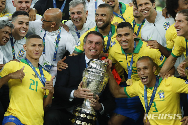 【리우데자네이루=AP/뉴시스】 7일(현지시간) 브라질 리우데자네이루 마라카낭 스타디움에서 자이르 보우소나루 대통령이 트로피를 들고 2019 코파 아메리카에서 우승을 차지한 브라질 선수들과 기념 촬영을 하고 있다. 이날 브라질은 페루를 3-1로 꺾고 통산 9회 우승을 차지했다.