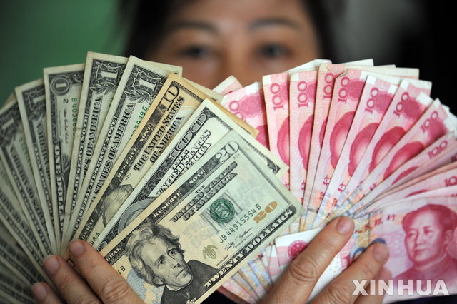 2016년 1월7일 중국 하이난성 충하이시에서 한 여성이 달러화와 위안화를 들어보이고 있다. (출처: 뉴시스)