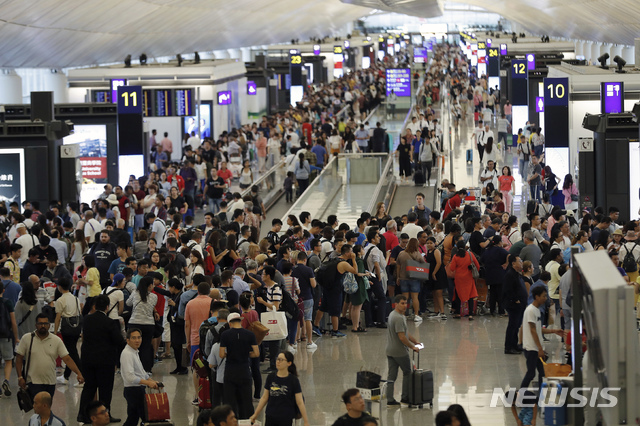 12일(현지시간) 홍콩 국제공항 출국장에 여행객들이 몰려들어 출국편 운항 정보를 확인하고 있다. 홍콩 국제공항은 이날 성명을 통해 5천여 명의 시위대가 공항에 모여 이로 인해 공항 운영이 “심각하게 방해