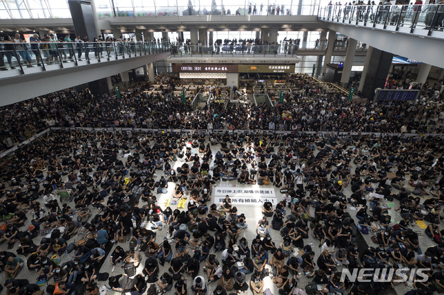 12일(현지시간) 홍콩 국제공항 입국장에 5천여 명의 홍콩 민주화 시위대가 앉아 연좌시위를 벌이고 있다. 홍콩 국제공항은 성명을 통해 이번 시위가 공항 운영을 “심각하게 방해했다”고 밝히며 이후 홍콩발 항공편에 대한 모든 탑승 수속 서비스를 중단했다. (출처: 뉴시스)