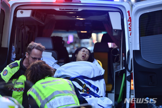 13일(현지시간) 호주 시드니 킹 앤드 요크가에서 흉기 난동이 일어나 부상한 한 여성이 고통스런 표정으로 구급차에 실리고 있다. 경찰과 목격자들은 칼로 무장한 한 젊은 남성이 
