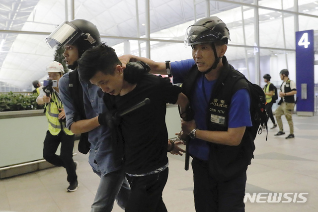 13일 밤 홍콩 국제공항에서 진압경찰이 '범죄인 인도법'에 반대하는 시위자를 연행하고 있다. 홍콩 국제공항은 시위대의 점거가 이어지면서 13일에도 극심한 혼란을 빚었다(출처: 뉴시스)