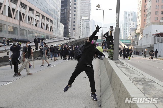 24일(현지시간) 홍콩 거리에서 한 시위 대원이 시위 중 경찰을 향해 돌을 던지고 있다. 시위대는 쿤통 등지에서 바리케이드를 치고 경찰과 대치했고, 경찰은 시위대를 향해 최루탄을 쏘며 진압을 시도했다. (출처: 뉴시스)