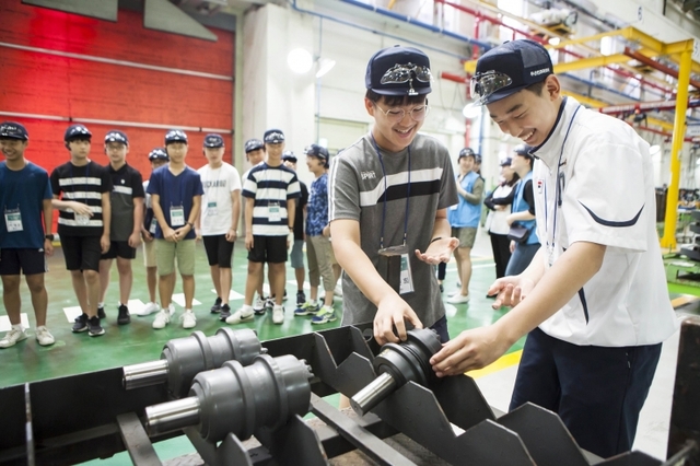 ‘Doosan Tomorrow Lab(두산과학교실)’에 참가하는 학생들이 지난해 8월 두산인프라코어 인천공장을 견학하며 건설기계 부품을 직접 만져보는 모습. (출처: 두산그룹)