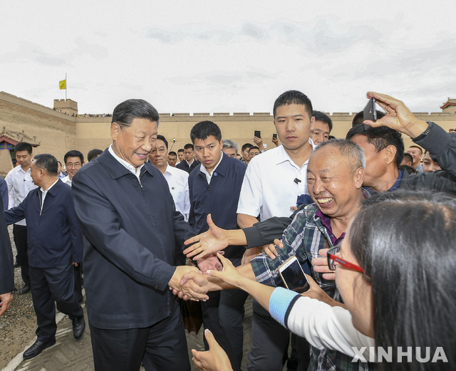 시진핑 중국 국가주석이 20일(현지시간) 중국 간쑤성 지아위관시를 방문해 시민들과 웃으며 악수하고 있다(출처: 뉴시스)