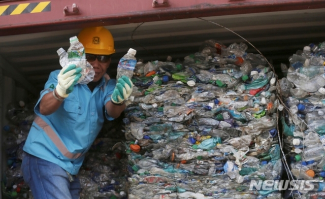 (자카르타=AP/뉴시스) 18일(현지시간) 인도네시아 자카르타의 탄중페락 항구에서 한 작업자가 플라스틱 쓰레기로 가득한 컨테이너 안에서 쓰레기들을 보여주고 있다. 인도네시아 정부는 폐플라스틱과 유해 물질이 들어찬 컨테이너 수백 개를 서구 국가들에 반송하고 있다. 중국이 지난해 폐플라스틱 수입을 중단하면서 선진국들이 동남아 국가로 폐기물을 수출하면서 필리핀과 인도네시아, 말레이시아 등이 골머리를 앓고 있다. 2019.09.18. 