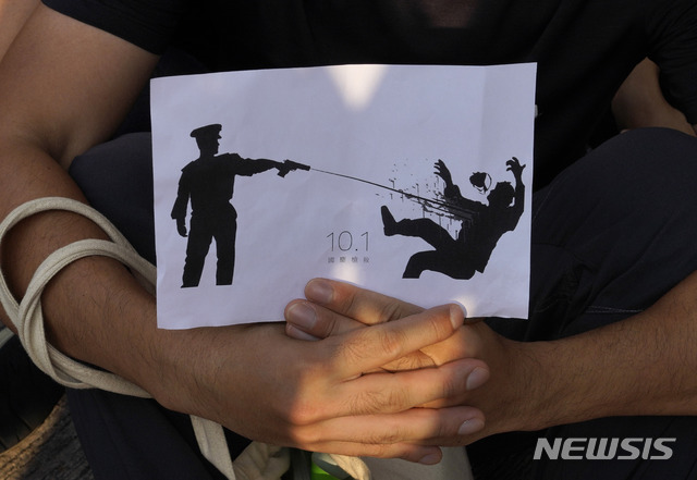 홍콩에서 2일 한 시위 참가자가 경찰이 시위자를 향해 총을 쏘는 모습을 묘사한 그림을 들고 있다. (출처: 뉴시스)