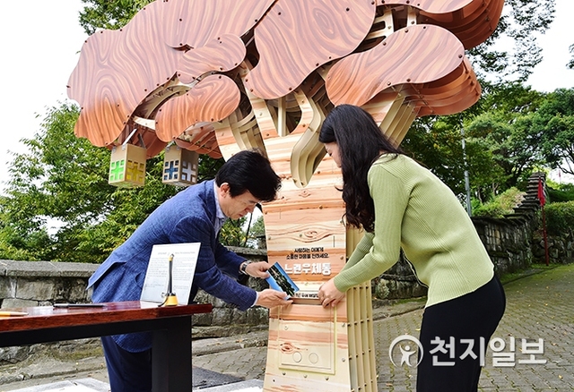 진주시가 지난 6월에 진주성 호국사 앞에서 갑자기 쓰러진 수령 600여년 느티나무 자리에 ‘느린 우체통’을 설치한 가운데 조규일 시장이 직접 작성한 편지를 우체통에 넣고 있다. (제공: 진주시) ⓒ천지일보 2019.10.7