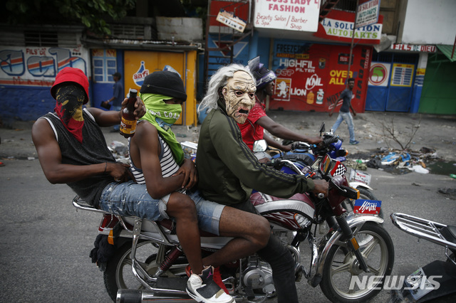 아이티 수도 포르토프랭스에서 마스크를 착용한 시위대가 오토바이를 타고 거리를 지나고 있다(출처: 뉴시스)
