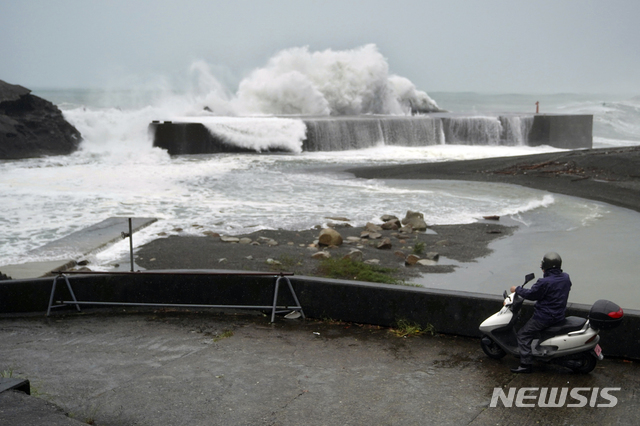 12일 일본 미에현 구마노 해변에 제19호 태풍 하기비스의 영향으로 거센 파도가 방파제를 덮치는 모습을 한 남성이 스쿠터에 앉아 바라보고 있다. (출처: 뉴시스)