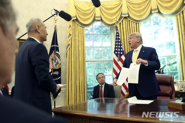 도널드 트럼프(오른쪽) 미국 대통령이 11일(현지시간) 백악관 집무실에서 류허 중국 부총리에게서 받은 문서를 들고 있다. (출처: 뉴시스)