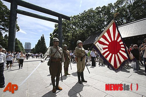 2014년 8월15일 옛 일본군 군복을 입은 일본 남성들이 2차 세계대전 종전 69주년을 맞아 전사자들에 대한 존경을 표하기 위해 과거 군국주의를 상징하는 욱일기를 들고 야스쿠니(靖國) 신사에서 행진을 벌이고 있다. (출처: 뉴시스)