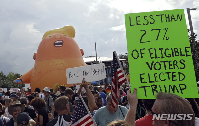 18일(현지시간) 미 플로리다주 올랜도의 암웨이센터 경기장에서 도널드 트럼프 미국 대통령의 2020년 대선 재선 캠페인 출정식이 열리는 가운데 행사장 밖에서 반 트럼프 시위대가 시위를 벌이고 있다. (출처: 뉴시스)