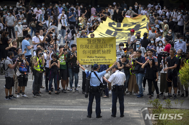 18일(현지시간) 홍콩 경찰이 홍콩 센트럴 구역에서 시위대를 향해 경고 손팻말을 들고 불법 집회에 대한 경고를 하고 있다. (출처: 뉴시스)