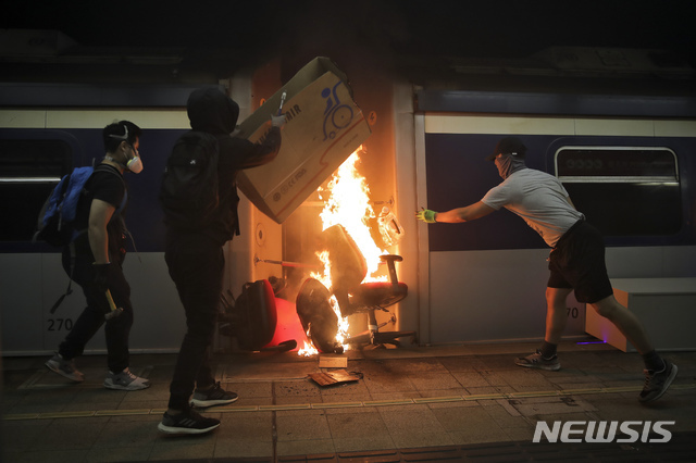 13일(현지시간) 홍콩의 중문대학 MTR 역 내에서 시위 학생들이 열차에 불을 지르고 있다. 시위대는 도로에 불붙은 바리케이드를 설치하고 열차를 부수거나 불을 지르는 등 대중교통을 방해해 도시 기능 마비를 시도하면서 최루탄과 물대포 등을 쏘며 저지하는 경찰과 충돌하고 있다. (출처: 뉴시스)