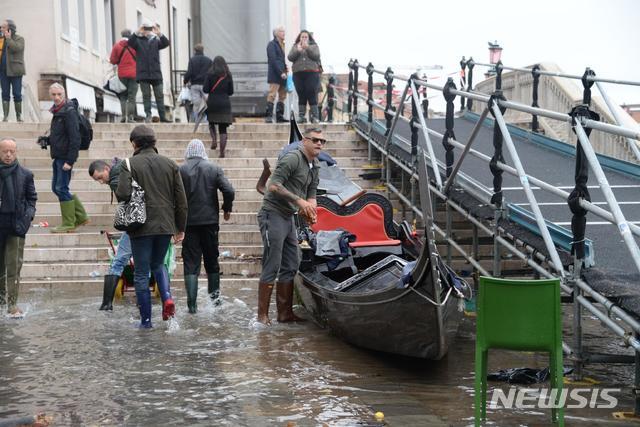 12일(현지시간) 이탈리아 베네치아에 지난 1966년 이래 최악의 홍수가 발생한 후 13일 한 남성이 곤돌라를 청소하고 있다. 전날 오후 조수 최고 수위가  187cm까지 올라 도시의 80% 이상이 물에 잠겼으며 이는 지난 1966년 198cm를 기록한 이후 최고 수준이다. (출처: 뉴시스)