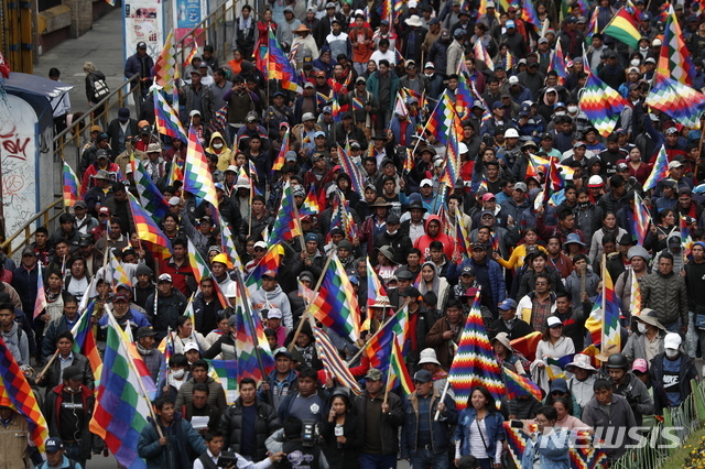 12일(현지시간) 볼리비아 수도 라 파스에서 에보 모랄레스 전 대통령의 지지자들이 볼리비아 토착민 깃발 '위팔라'를 들고 그의 사임에 반대하는 시위를 벌이며 행진하고 있다. (출처: 뉴시스)