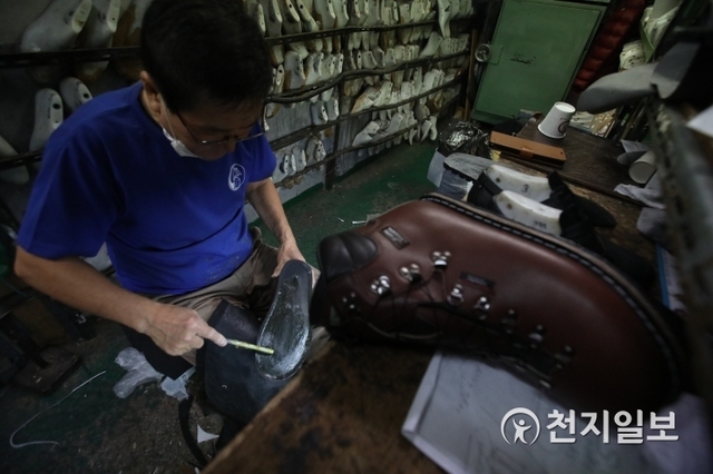 [천지일보=남승우 기자] 신발 겉창을 붙이기 위해 접착제를 바르고 있는 모습. ⓒ천지일보 2019.12.1