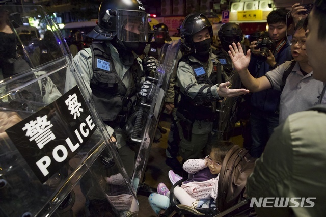 1일(현지시간) 홍콩주민들이 집으로 돌아가는 도중 경찰과 말싸움을 벌이는 가운데 한 어린이가 귀를 막고 있다. (출처: 뉴시스)