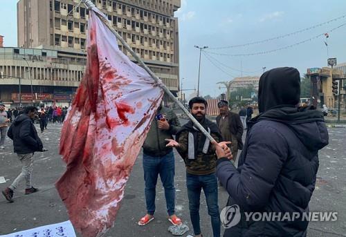 바그다드 킬라니 광장에서 피 묻은 깃발을 들고 있는 시민. (출처: 연합뉴스)