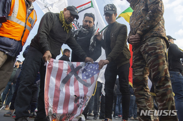 지난 4일(현지시간) 이란의 거셈 솔레이마니 혁명수비대 쿠드스군 사령관의 추모 행사가 벌어진 이라크 바그다드에서 몇몇 시민들이 미국의 성조기를 불태우고 있다. (출처: 뉴시스)