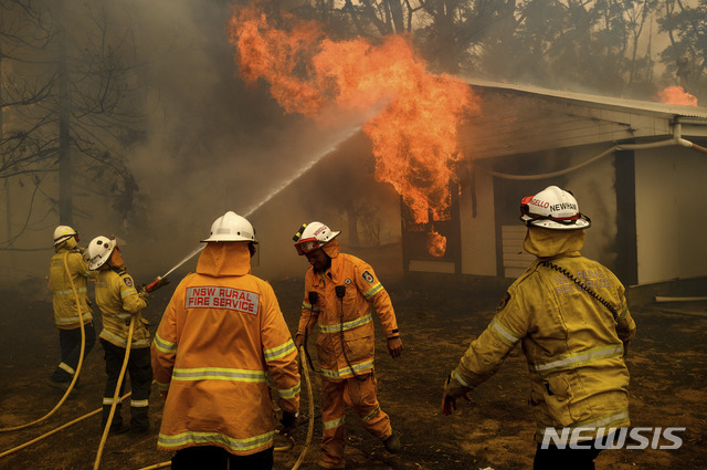 23일(현지시간) 호주 뉴사우스웨일스주 번더눈에서 소방관들이 주택을 덮친 화재를 진압하려고 애쓰고 있다. 현재 호주 수도 캔버라 일대에서 발생한 산불이 확산하고 있다(출처: 뉴시스)