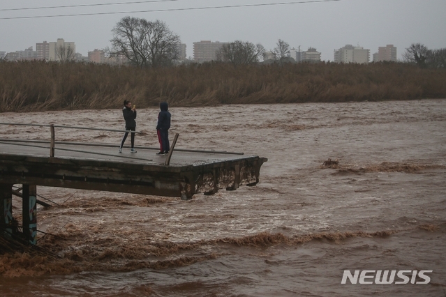 22일 스페인 바르셀로나 인근 말그라트에서 폭우로 붕괴된 다리 위에서 남성 2명이 사진을 찍고 있다(출처: 뉴시스)