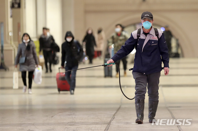 신종 코로나바이러스가 발생한 중국 후베이성 우한시의 지하철역에서 22일 한 사람이 소독약을 뿌리고 있다. 뒤에 감염을 막으려고 마스크를 쓴 행인들이 보인다. (출처: 뉴시스)