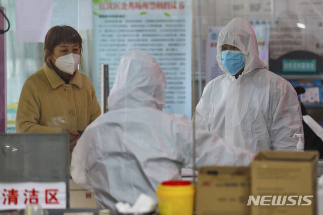 중국 우한의 한 보건소에서 27일 환자로 보이는 한 여성과 의료진이 나란히 서있다. (출처: 뉴시스)