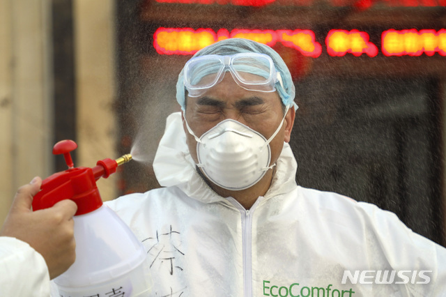 중국 후베이성 우한의 한 격리시설에서 3일 보호복을 입은 한 의료 요원이 소독약이 뿌려지는 동안 눈을 감고 있다. 우한의 의료진은 신종 코로나 사태로 격무와 감염 위험에 시달리고 있다(출처: 뉴시스)