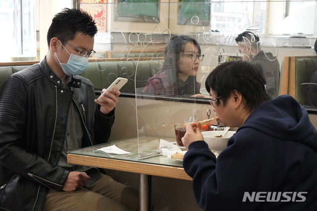 [홍콩=AP/뉴시스] 12일(현지시간) 홍콩의 한 식당에서 식당 손님들이 신종 코로나바이러스 감염증(코로나19)의 전파를 막기 위해 투명 플라스틱 칸막이가 설치된 테이블에서 식사하고 있다.