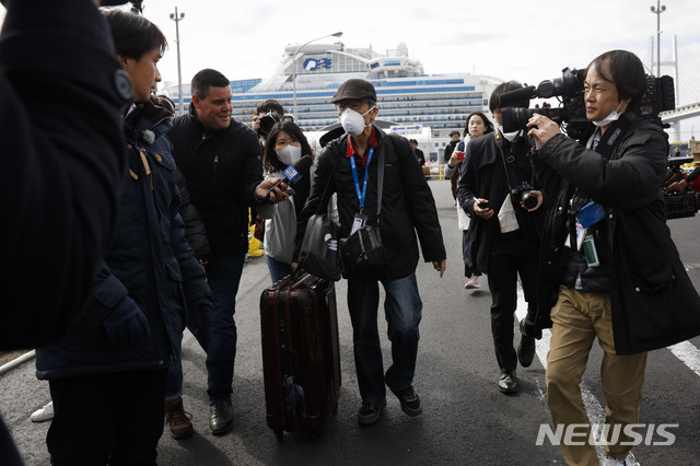 19일(현지시간) 일본 요코하마항에 정박 중인 유람선 다이아몬드 프린세스호에서 하선한  승객들이 취재진에 둘러싸여 있다. 이날 신종 코로나바이러스 감염증(코로나19) 검사에서 음성 판정을 받은 유람선 승객 약 500명이 오전부터 유람선에서 하선하고 있다(출처: 뉴시스)