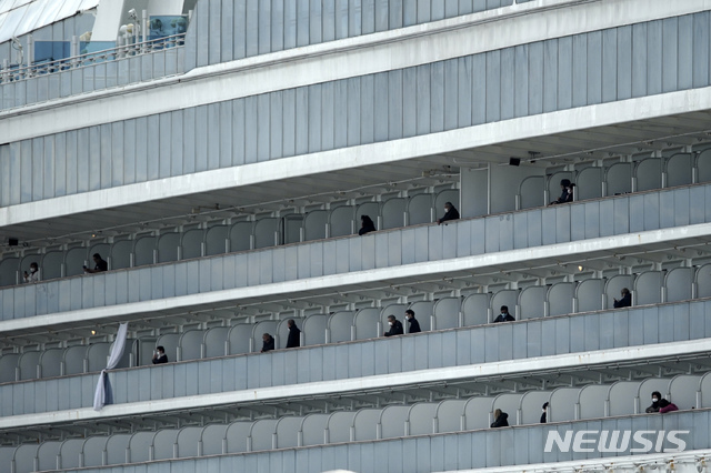 19일 일본 요코하마항에 정박 격리중인 크루즈선 다이아몬드 프린세스호에서 승객 하선이 시작된 가운데 일부 승랙들이 발코니에 나와 밖을 바라보고 있다. 이날도 양성반응 승객이 무더기로 나와 총 확진자가 621명에 달했다. (출처: 뉴시스)