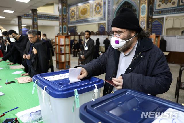 21일(현지시간)  이란 수도 테헤란의 한 투표소에서 마스크를 쓴 한 남성이 투표하고 있다. 이날 이란 의회 의원을 뽑는 선거가 열려 4년 임기의 의원 290명을 뽑는다. 이란은 만 18세 이상 남녀는 모두 참정권을 행사할 수 있으며 이번 총선에서 5천800만 명이 유권자로 등록됐다. (출처: 뉴시스)