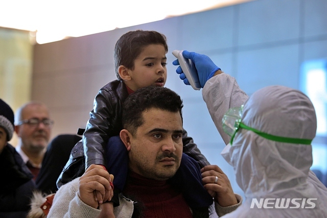 21일(현지시간) 이라크 나자프의 나자프 공항에서 방호복을 입은 한 의료종사자가 이란에서 입국하는 승객들에 대해 체온 검사를 하고 있다. (출처: 뉴시스)