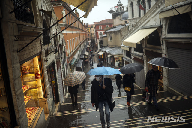1일(현지시간) 이탈리아 북부 베테토주에 비가 오는 가운데 리알토 다리에서 시민들이 마스크를 착용하고 우산을 쓴 채 걷고 있다. 이 지역에서는 신종 코로나바이러스 감염증(코로나19) 확진자가 다수 나왔다. (출처: 뉴시스)