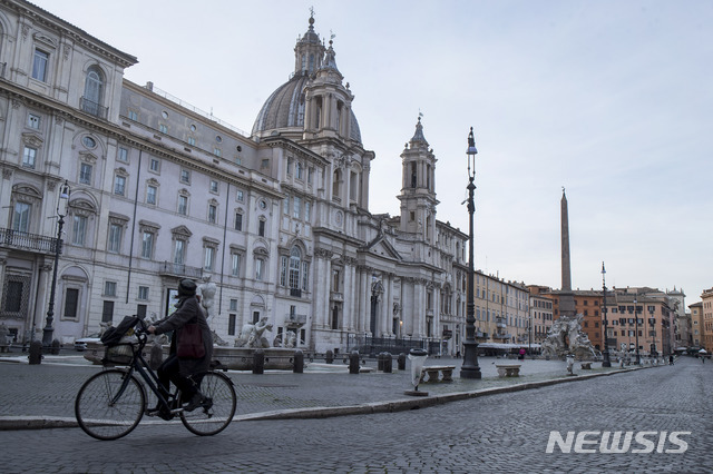 코로나19의 급한 확산으로 이동금지령이 내려진 채 텅빈 이탈리아 로마 시내 중심가의 나보나 광장을 12일(현지시간) 한 여성이 자전거를 타고 지나가고 있다. (출처: 뉴시스)