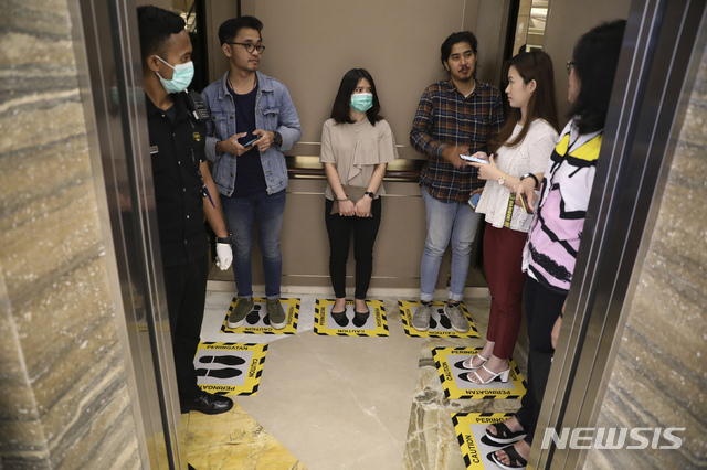 [수라바야=AP/뉴시스] 19일(현지시간) 인도네시아 수라바야의 한 쇼핑몰 엘리베이터에서 사람들이 신종 코로나바이러스 감염증의 확산을 막기 위한 '사회적 거리 두기'의 일환으로 바닥의 지정된 장소에 서 있다. 2020.03.19.