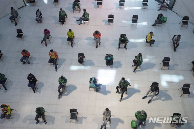24일(현지시간) 태국 방콕의 한 쇼핑몰 포장 음식 대기 구역에서 사람들이 신종 코로나바이러스 감염증의 확산을 막기 위해 지정 구역에 배치된 의자에 앉으며 사회적 거리 두기 실천 연습을 하고 있다. (출처: 뉴시스)